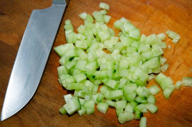 İngiliz salatalığını Santoku bıçağıyla doğramak: Bambu kesme tahtasındaki organik çekirdeksiz salatalığı ince ince doğramak