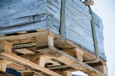 Kamyondan kaldırım levhaları indiriyorum. Erkekler kaldırım levhalarını manipülatör kullanarak boşaltır. İşçiler inşaat malzemelerini büyük bir makineden boşaltıyorlar.