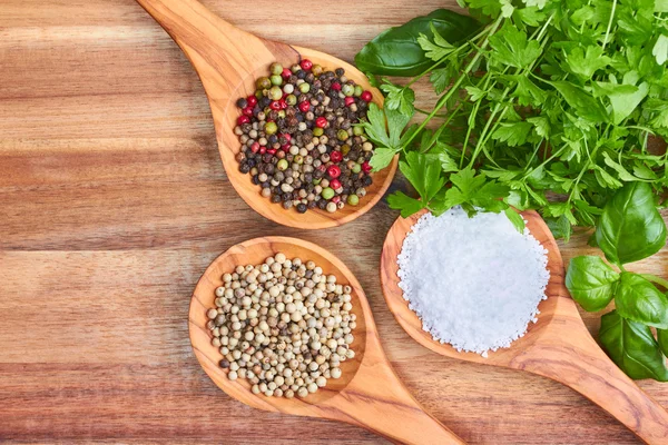 Spices, parsley, basil and sea salt in spoons on wooden backgrou Stock Photo
