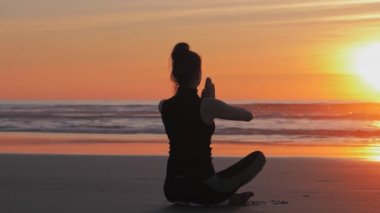 Gün batımında plajda yoga pratiği.