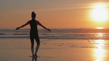 Güzel gün batımında sahilde ince bir kadının silueti.