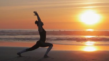 Yoga pratiği, kumsalda kollarını kaldırmış bir kadın.