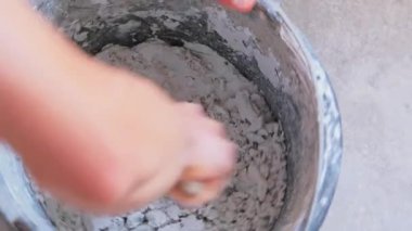 Erkek elleri kovada çimentoyu karıştırıyor
