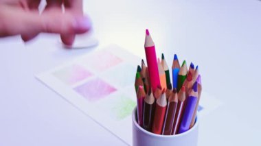 Renkli kalem çeşitleri var. Dişi el, kurşun kaleme basıyor.