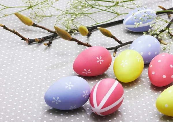 Uova di Pasqua colorate su sfondo con fiori primaverili — Foto Stock