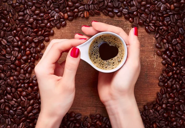 Woman holding hot cup of coffee with heart shape — Stock Photo, Image