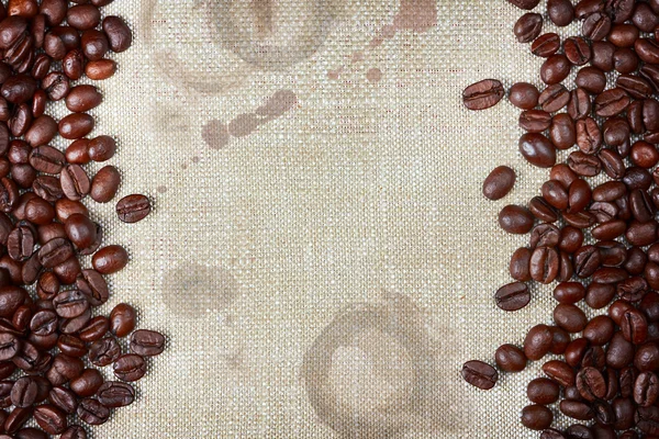 Granos de café y arpillera con manchas de café y bordes ásperos — Foto de Stock