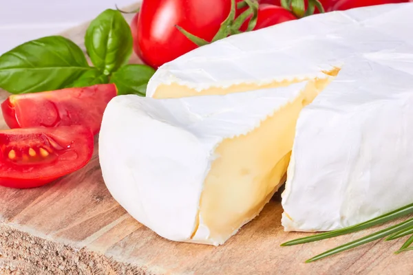 Queso de cabra, tomate cherry y albahaca en una tabla de madera —  Fotos de Stock