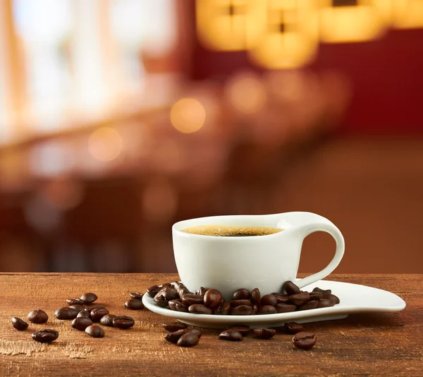 Xícara quente de café no fundo do café borrão — Fotografia de Stock