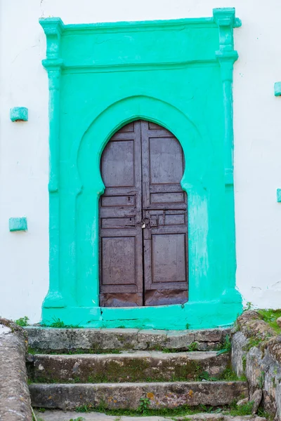 Старая деревянная дверь на зеленой покрашенной стене — стоковое фото