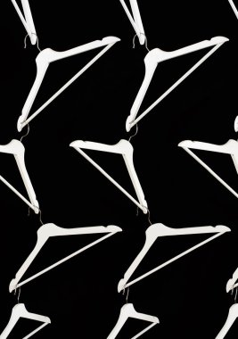 En düşük moda kıyafetleri konsepti. Siyah arka planda beyaz elbise askısı var. Moda blogu, web sitesi, sosyal medya kahramanı başlığı. Askı deseni.