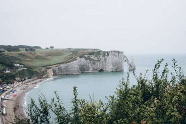 Falaise d 'Aval kıyısındaki kıyı manzarası Etretat köyünün ünlü beyaz uçurumları, Porte d' Aval doğal kemeri ve Aiguille d 'Etretat, Normandie, Fransa olarak bilinen kaya ile.