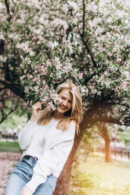 Parka bakan güzel bir genç kadının portresi. Gülümseyen bir kızın portresi. Parkta gülen mutlu kız. Bahar günü. Yaz tatili. Yaşam biçimi.