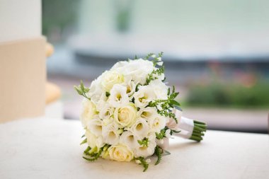 Masanın üzerinde güzel yuvarlak balo gelin buketi var. Çiçekli düğün dekoru. Mesaj atılacak yer, düğün nitelikleri. Romantik bir buket beyaz gül ve mutluluk.