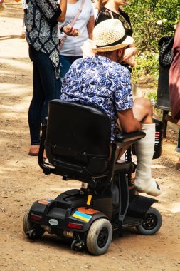 Bacağı kırık alçılı bir adam elektrikli sandalyeyle seyahat eder. Engelliler için seyahat. Toplumdaki engelli kızların koltuk değnekleriyle uyum sağlaması