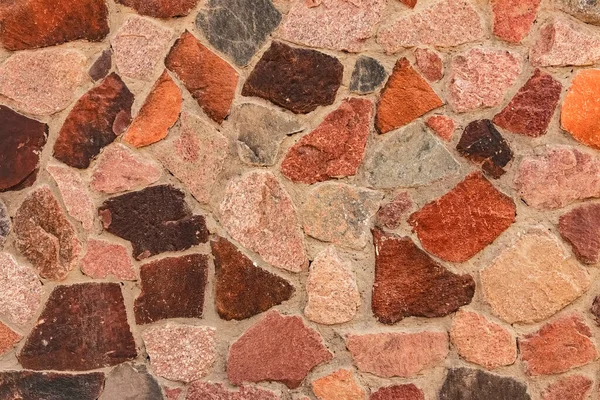 Decorative wall cladding with large granite stones. Mosaic background from large colored natural stones. Decorative cladding with multi-colored granite. Wall decoration with colored granite.