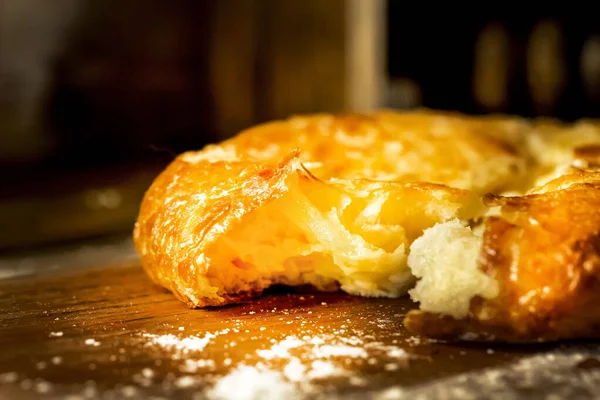 Kırık bir Türk peynirli keki ahşap bir masada yatıyor. Eski ahşap bir masada peynirli kırık pide. Gürcü Khachapuri, kubdari, peynirli lobiani. Peynirli lezzetli ekmek. Ev yapımı pişirme