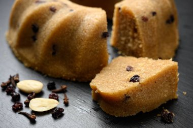 Kuru üzümlü ev yapımı irmik halkası fındıklı siyah tabakta servis edilir.