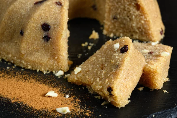 Tarçınlı ve fındıklı siyah tabakta servis edilen kuru üzümlü ev yapımı irmik halkası.