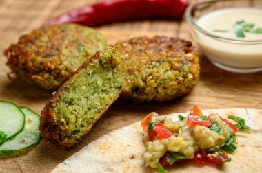 Pide ekmeği, domates, salatalık, marul, ızgara patlıcan salatası ve tahin sosuyla servis edilen ev yapımı falafel.