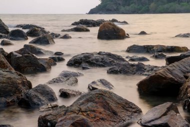 Gün batımından önce kayanın yakınındaki dalgalar. Yumuşak odaklanma.