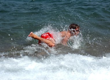 Genç çocuk dalgalarla oynuyor.