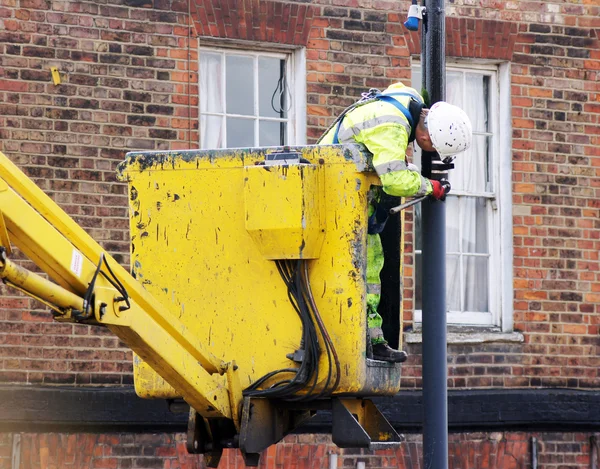 Trabalhador pinta uma lâmpada de rua — Fotografia de Stock