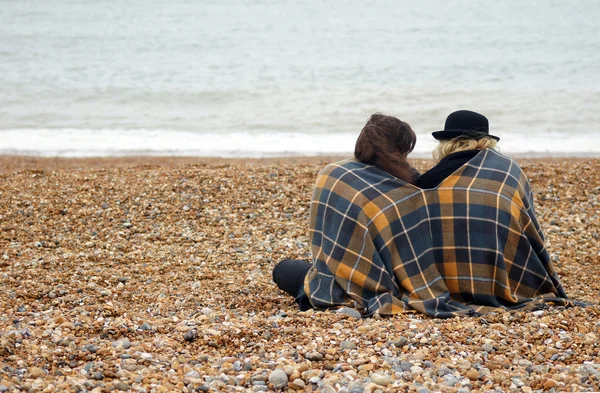 Vänner sitter på stranden — Stockfoto