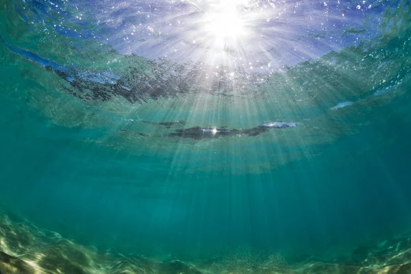 Underwater view of water surface with ripples mirrors and bright sun in clear sea — Stock Photo, Image