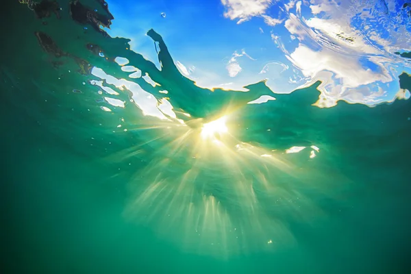 Solstrålar lyser genom vattenytan ocean — Stockfoto