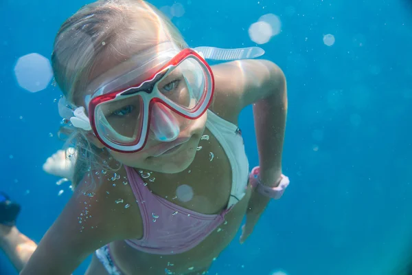 Una piccola ragazza bionda carina di sette anni che indossa una maschera di vetro sott'acqua nel mare — Foto Stock