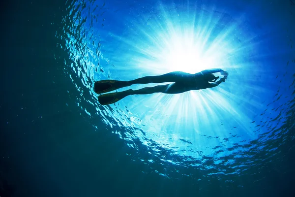 水面下の太陽を持つフリーダイバーのシルエット — ストック写真