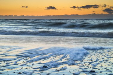 Huzurlu ve huzurlu Zen-benzeri bir gün batımı plajda, su üzerinde güzel yansımaları olan Kuzey Denizi, Hollanda