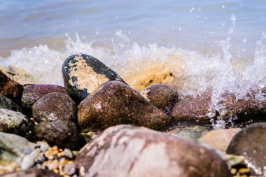 Dalgalar bir plajda sıçramasına ile renkli taş