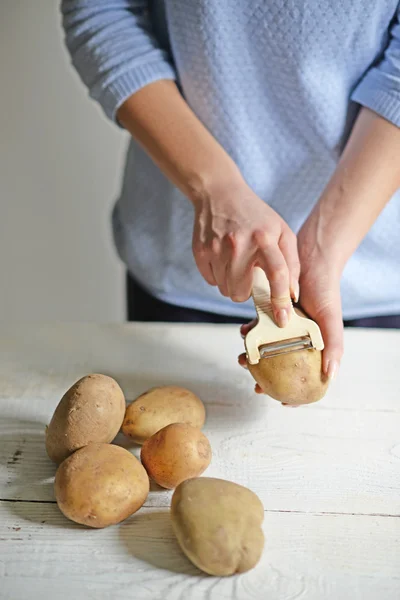 Женщина чистит картошку для кипения — стоковое фото