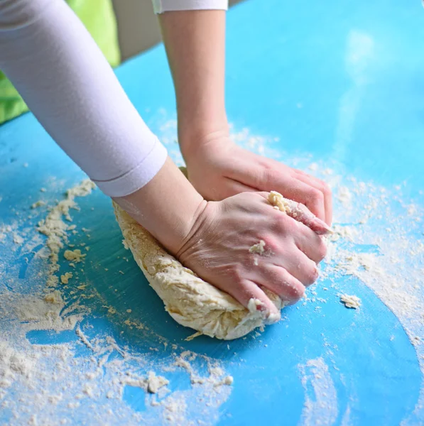 Las manos de la mujer amasan la masa sobre la mesa — Foto de Stock