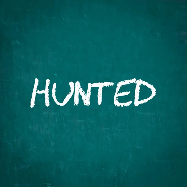 HUNTED ditulis pada papan tulis — Stok Foto