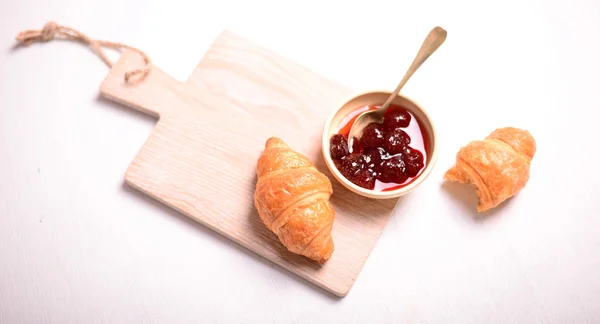 Frühstück mit frischen Croissants und Marmelade auf weißem Hintergrund — Stockfoto