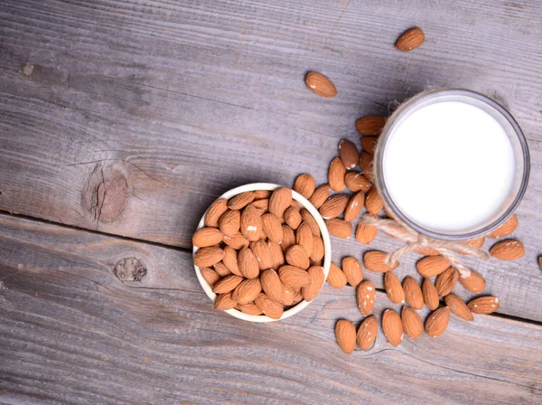 Leche de almendras en vaso con almendras sobre mesa de madera —  Fotos de Stock