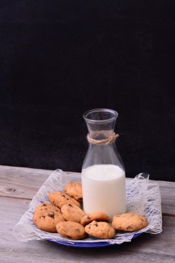 Şişe süt rustik masada kurabiye ile