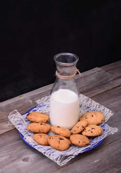 Bottle of milk with cookies on rustic table — Stock Photo, Image