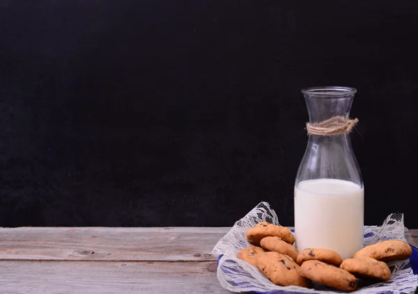 Flaska mjölk med cookies på rustika bord — Stockfoto