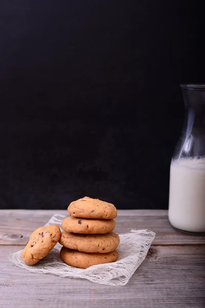 Csokoládé cookie-kat, a csipke szalvéta üveg tejet a háttérb — Stock Fotó