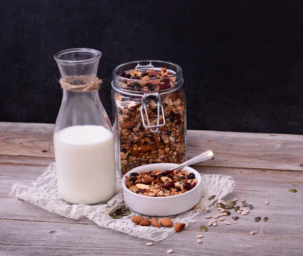 Muesli granen met fles melk op houten tafel — Stockfoto