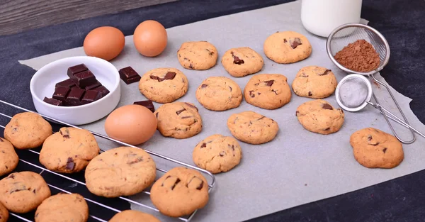 Inicio galletas de chocolate horneado e ingredientes sobre papel de hornear en — Foto de Stock