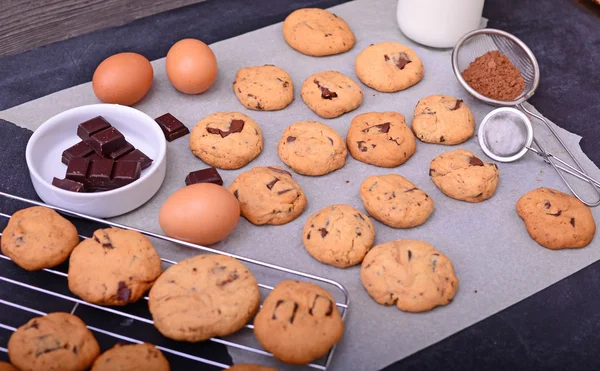 Inicio galletas de chocolate horneado sobre papel de hornear con ingredientes en — Foto de Stock