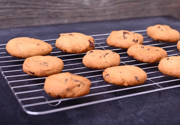 Casa biscoitos de chocolate cozidos no rack de refrigeração no fundo preto — Fotografia de Stock