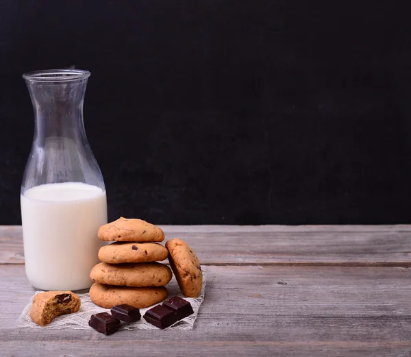 Στοίβα των σοκολατένιων μπισκότων και μπουκάλι γάλα στο blackboard — Φωτογραφία Αρχείου