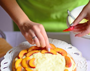 Woman hand put peach on the cake crust clipart