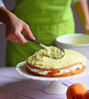 Woman hand put pudding on the cake crust - peach cake prepare clipart